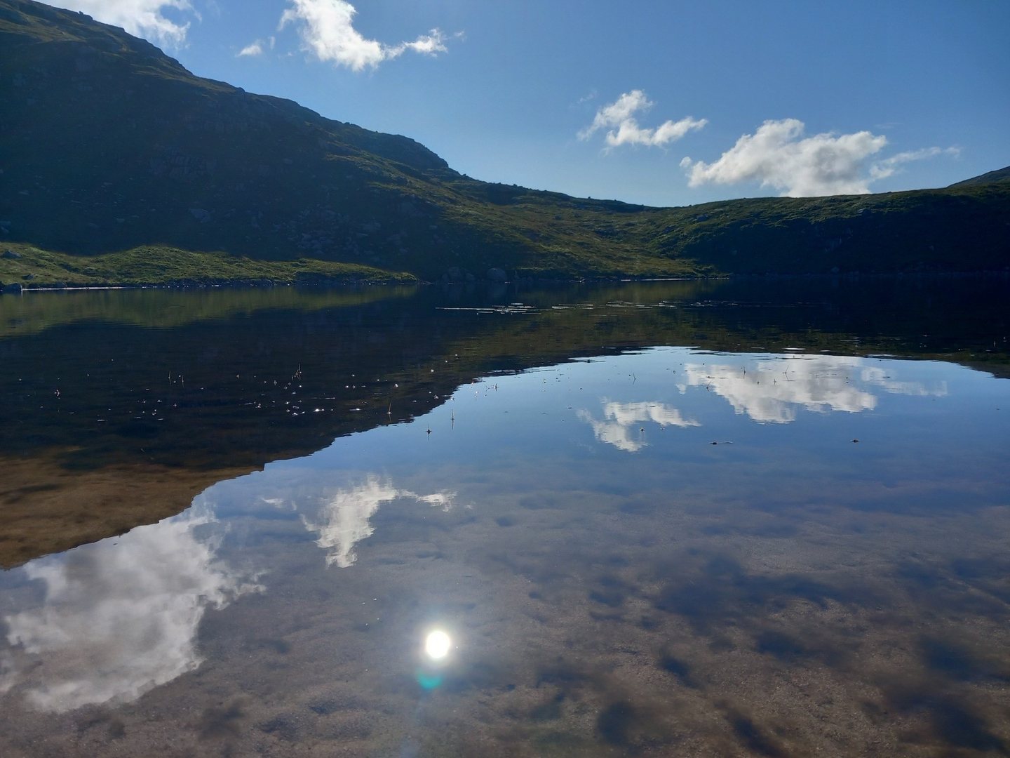Quiet mountain lake reflecting a blue sky and clouds